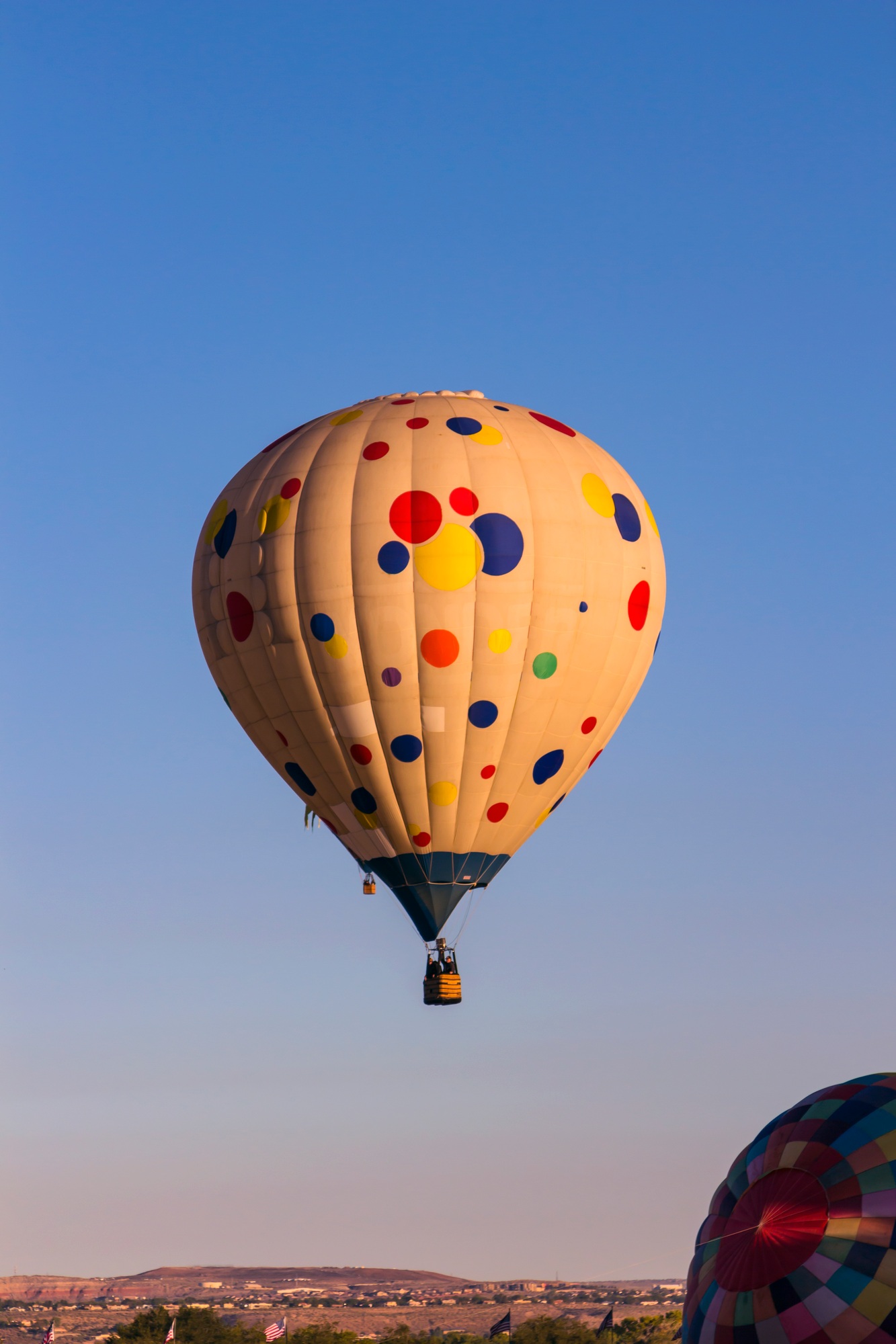 Beautiful shot of hot air balloons in colorful patterns floating on background of the clear blue sky